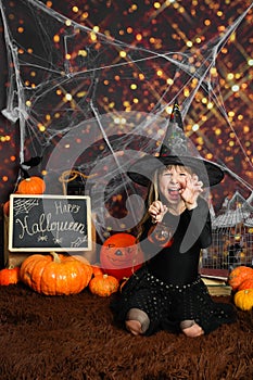 Portrait of an angry little girl in a witch costume, on Halloween background.