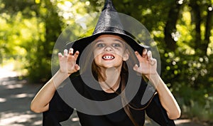 Portrait of an angry little girl in a witch costume, outside. halloween