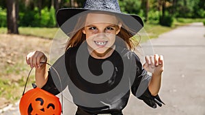 Portrait of an angry little girl in a witch costume, on outside. happy halloween