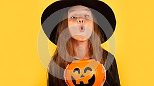 Portrait of an angry little girl in a witch costume, on a yellow background. Happy halloween