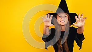 Portrait of an angry little girl in a witch costume, on a yellow background. Happy halloween