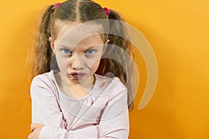portrait of an angry little girl on a yellow background, emotions in children