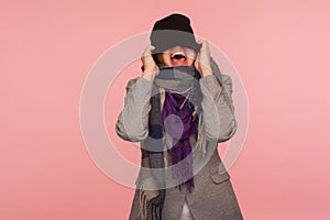 Portrait of angry mad girl in scarf pulling hat over her eyes and shouting, feeling crazy pissed off and desperate