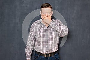 Portrait of angry man covering mouth, not wanting to say photo