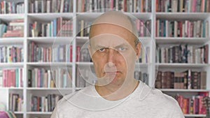 Portrait angry man face looking into camera on bookcase background