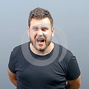 Portrait of a angry man screaming against gray background