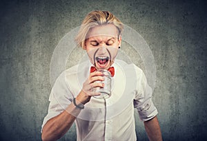 Portrait of an angry man screaming into empty glass jar