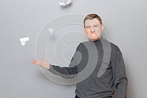 Portrait of angry mature man throwing up crumpled pieces of torn paper