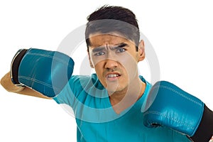 Portrait of angry sportsman in blue gloves and uniform practicing boxing on camera isolated on white background