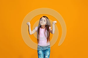Portrait of angry teen girl on a orange studio background