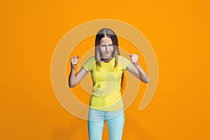 Portrait of angry teen girl on a orange studio background