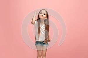 Portrait of angry teen girl on a pink studio background