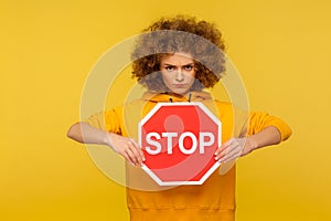 Portrait of angry woman holding red Stop sign and looking at camera with negative aggressive expression