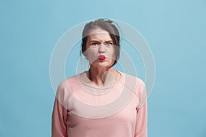 Portrait of an angry woman looking at camera on a blue background