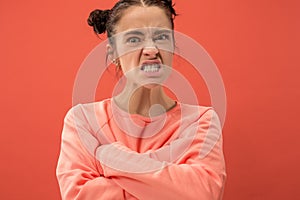 Portrait of an angry woman looking at camera isolated on a coral background