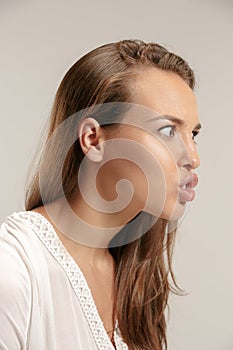 Portrait of an angry woman looking at camera isolated on a gray background