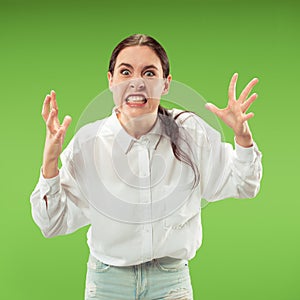 Portrait of an angry woman looking at camera isolated on a green background