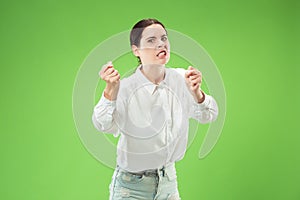 Portrait of an angry woman looking at camera isolated on a green background