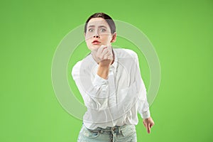 Portrait of an angry woman looking at camera isolated on a green background