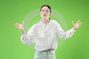 Portrait of an angry woman looking at camera isolated on a green background