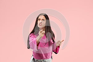 Portrait of an angry woman looking at camera on a pink background