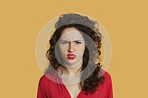 Portrait of angry young woman frowning over colored background