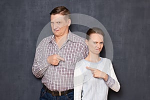 Portrait of annoyed man and woman pointing at one another