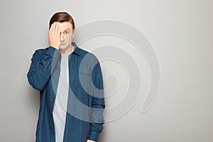 Portrait of anxious man covering half of his face with hand