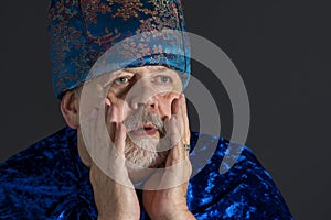 Portrait of anxious senior man in blue oriental clothes