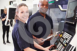 Portrait Of Apprentice Working With Engineer On CNC Machine