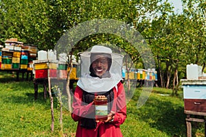 Portrait of Arab investitor in the beekeeping department of a honey farm holding a jar of honey in her hand