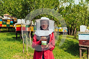 Portrait of Arab investitor in the beekeeping department of a honey farm holding a jar of honey in her hand