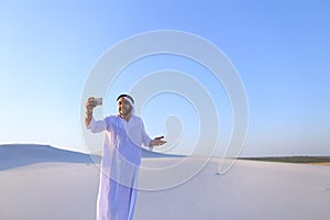 Portrait of Arabian sheikh man with gadget that communicates in