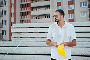 Portrait of an architect builder studying layout plan of the rooms, serious civil engineer working with documents on