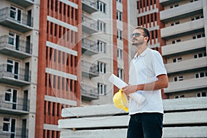 Portrait of an architect builder studying layout plan of the rooms, serious civil engineer working with documents on