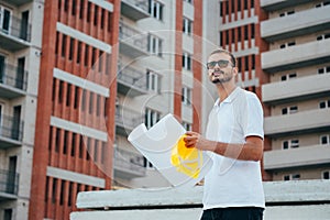 Portrait of an architect builder studying layout plan of the rooms, serious civil engineer working with documents on