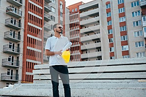 Portrait of an architect builder studying layout plan of the rooms, serious civil engineer working with documents on