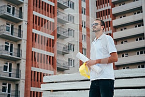 Portrait of an architect builder studying layout plan of the rooms, serious civil engineer working with documents on construction