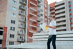 Portrait of an architect builder studying layout plan of the rooms, serious civil engineer working with documents on construction