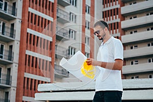 Portrait of an architect builder studying layout plan of the rooms, serious civil engineer working with documents on construction