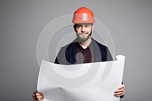 Portrait of an architect builder studying layout plan of the rooms, serious civil engineer working with documents on construction