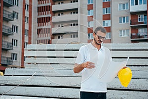 Portrait of an architect builder studying layout plan of the rooms, serious civil engineer working with documents on construction