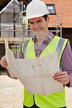 Portrait Of Architect On Building Site Looking At House Plans