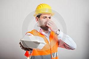 Portrait of architect handing bad smelling lunch box