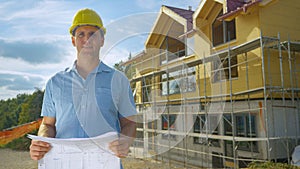 PORTRAIT Architect holding plans while standing outside house under construction