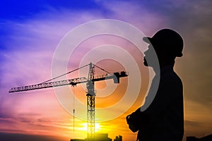 Portrait of architect silhouette wear a helmet at construction site with crane background and sunset