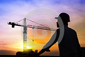 Portrait of architect silhouette wear a helmet at construction site with crane background and sunset