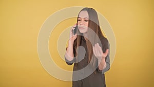 Portrait of arcing aggressive women talking on the phone on yellow background