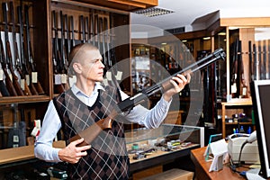 Portrait of an arms shop salesman with pump-action shotgun in hands