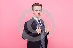 Portrait of arrogant young businessman in expensive suit looking supercilious and self-confident. indoor studio shot isolated on photo